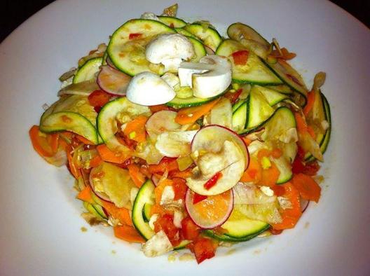 Rå salat lavet af squash, radise, fennikel, gulerødder og champignon med tomat og avocado stykker masseres i det ...